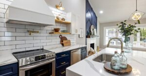 A modern kitchen featuring marble countertops, a stainless steel stove, and elegant blue cabinets.