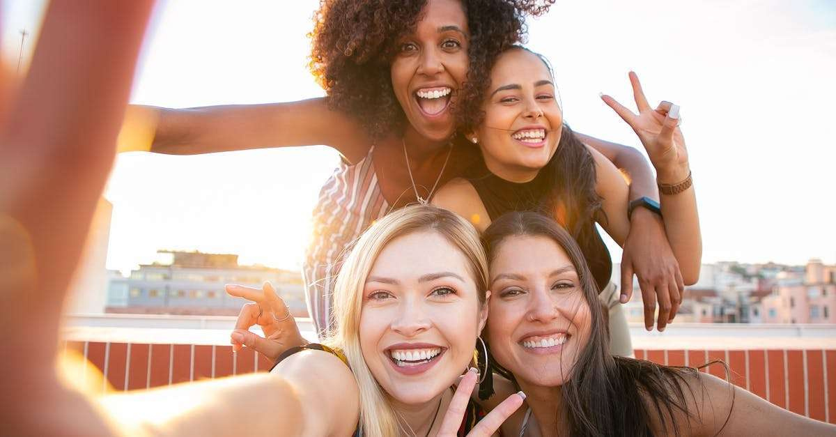 Build Strong Social Connections,Cheerful friends capturing a fun selfie on a rooftop during sunset, enjoying a positive and trendy moment.