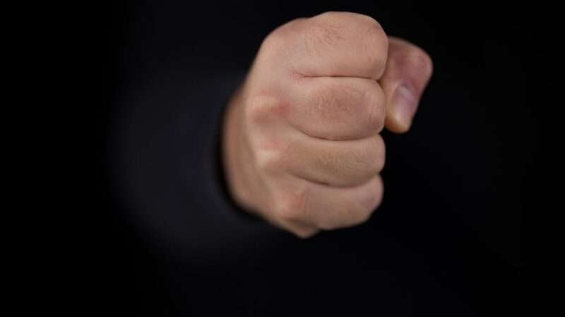 Detailed close-up of a clenched fist on a black background showing strength and determination.