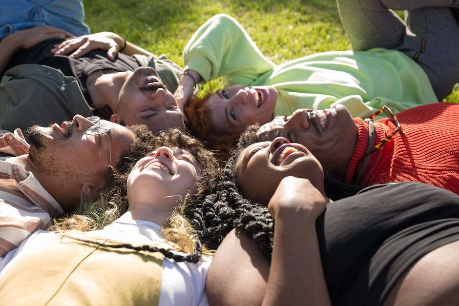 A diverse group of friends laughing and bonding together in a sunny outdoor setting.